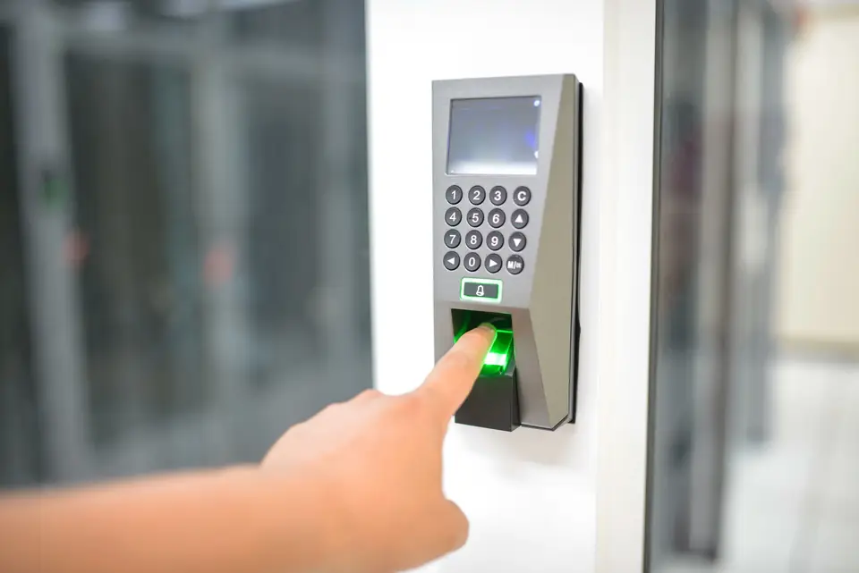 Finger pressed on a fingerprint access reader glowing green