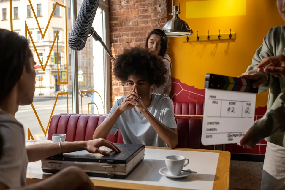 Film crew in a café set with a clapperboard and boom microphone