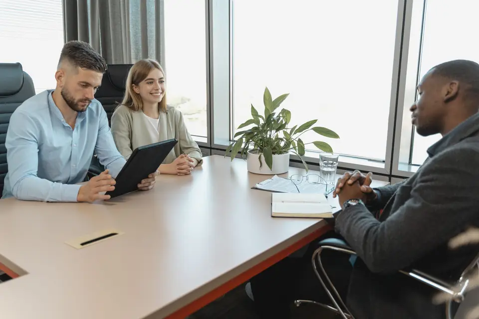Hiring panel interviewing a candidate, one panellist holding a tablet