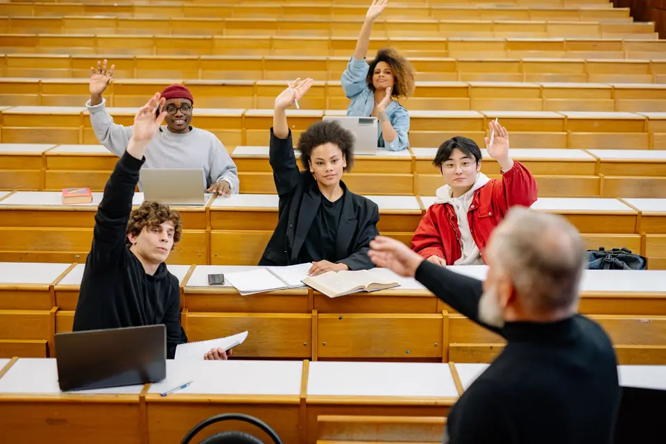 University students raising their hands in a lecture hall