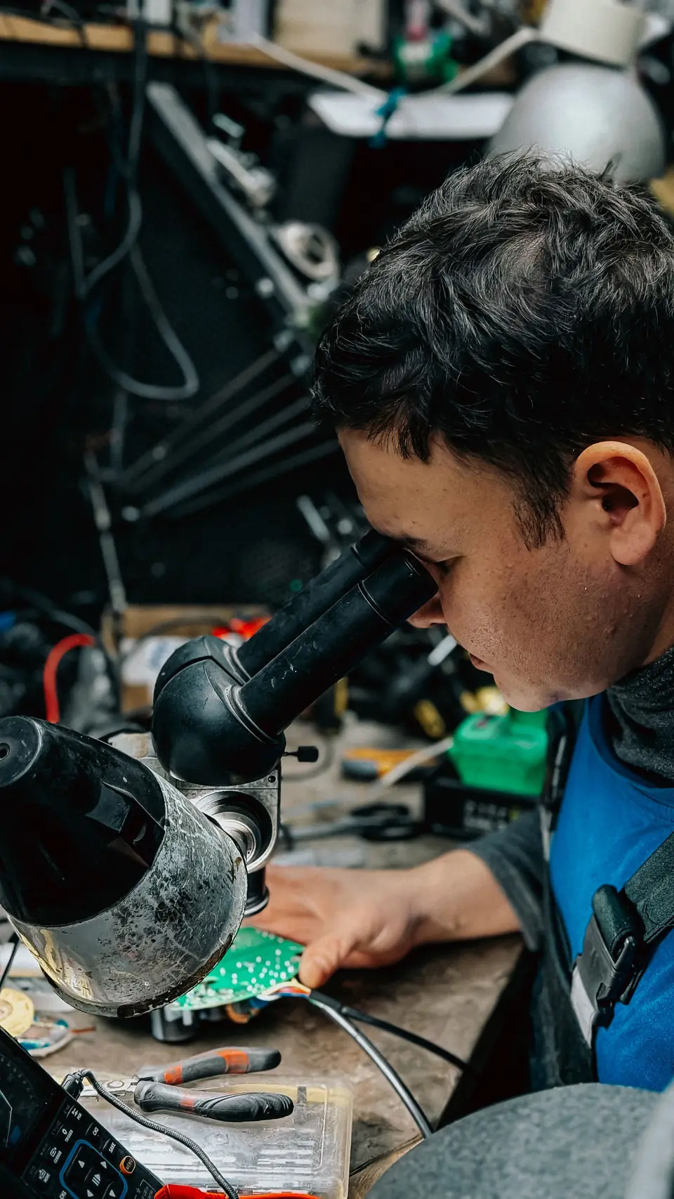 Technician inspecting a circuit board under a microscope
