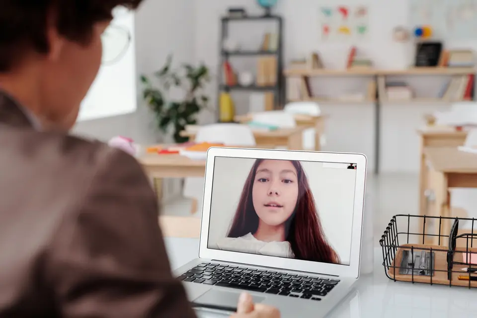 Teacher giving a lesson to a pupil over a video call on a laptop